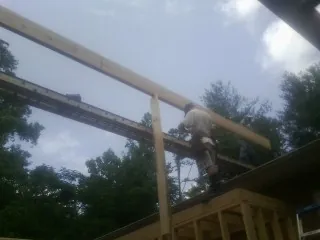 Carpenter setting a ridge beam over a new addition frame — Ice Dam Removal by Roofing Brothers in Lawler