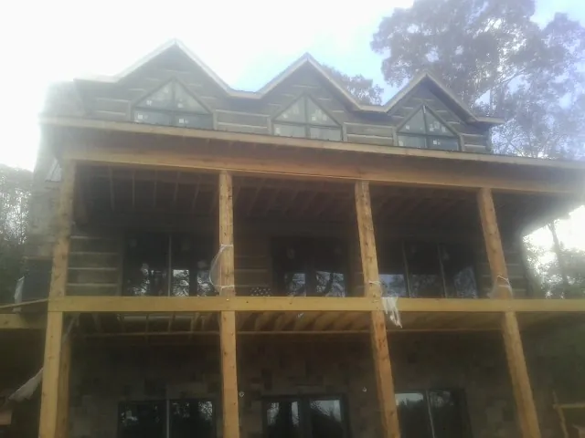 Dormers and porch framing on a large log home under construction — Roof Coating work by our crew in Lawler