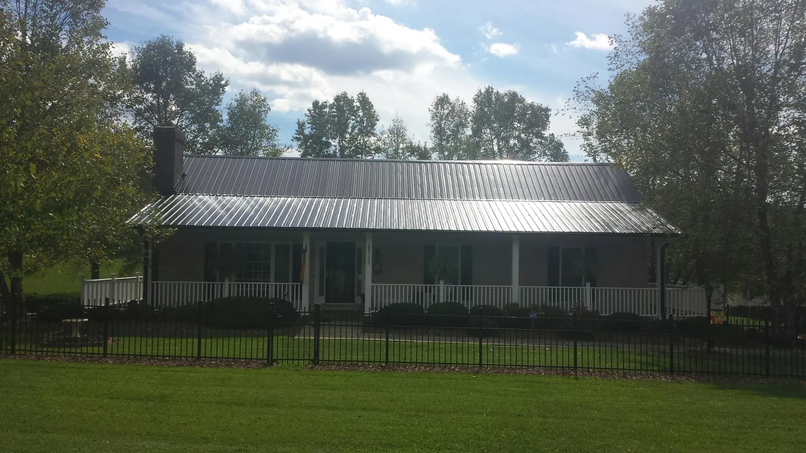 Gray metal roof on a brick ranch with a full width front porch — Gutter Guard Installation work by our crew in Lawler