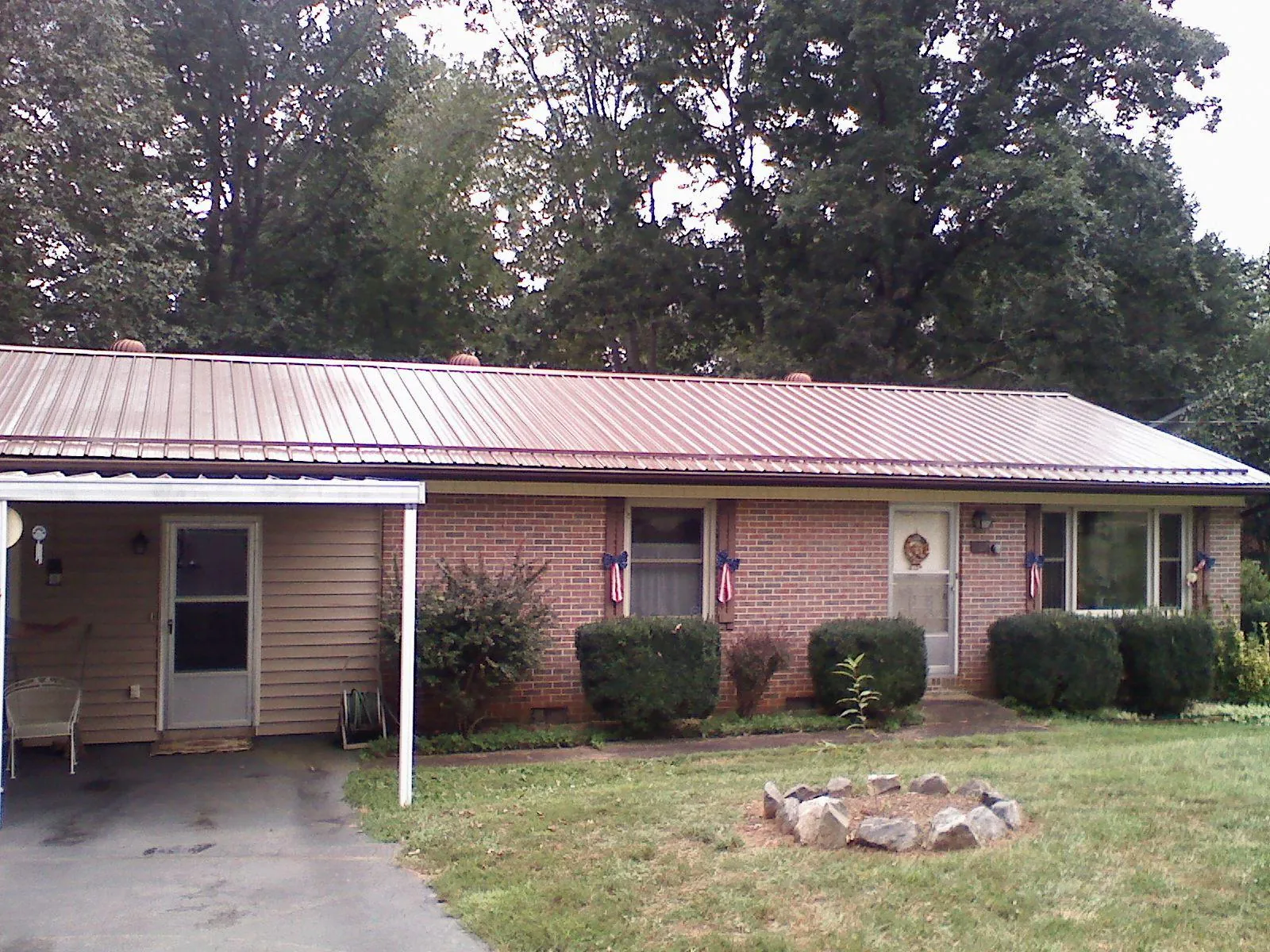 Bronze metal roof and carport on a brick ranch home — Roof Repair work by our crew in Lawler