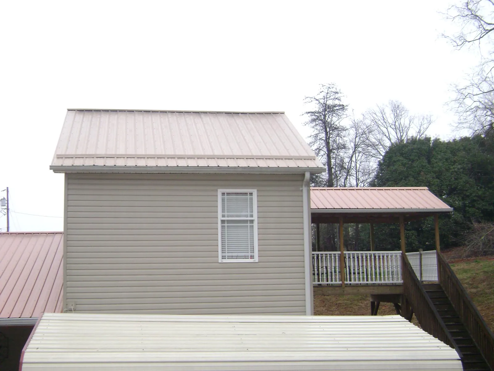 Tan metal roofs on a two story addition and attached porch, from a Roof Replacement job in Lawler