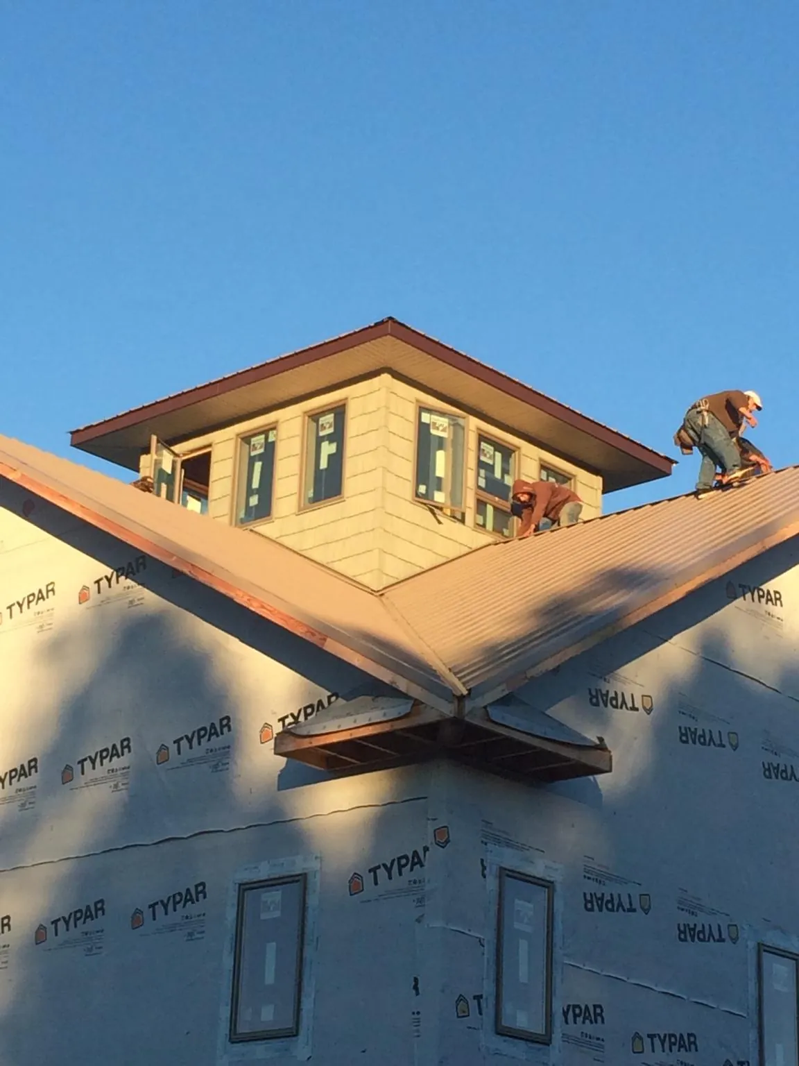 Roofers working around a rooftop cupola on a new metal roof at sunset — Roof Waterproofing in Lawler by Roofing Brothers